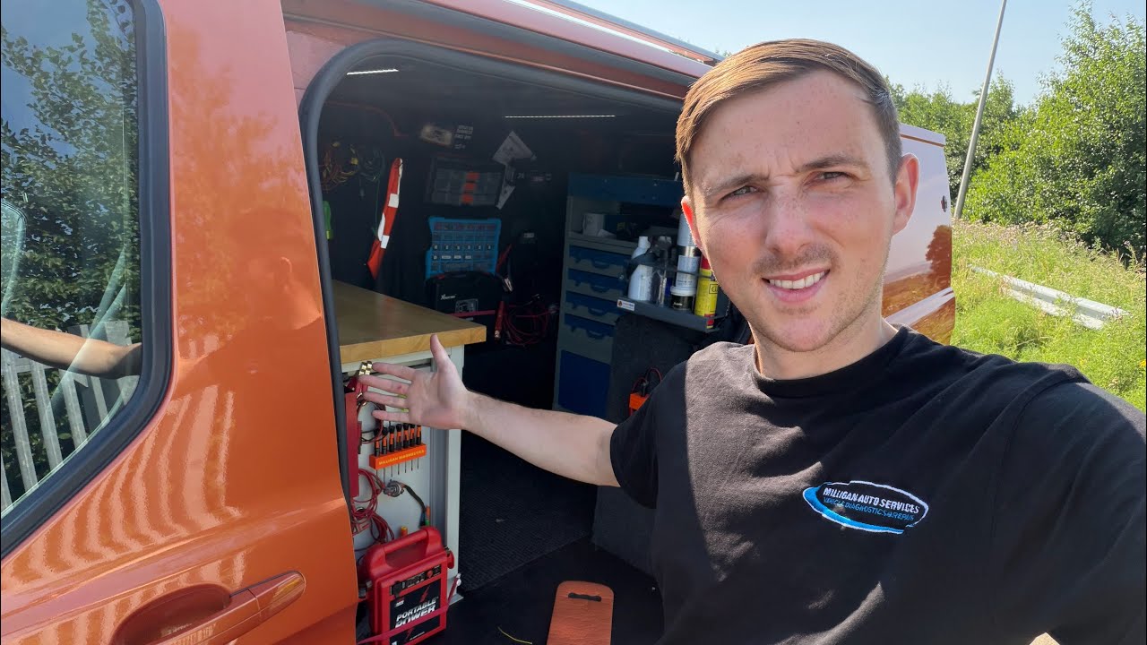 A technician from Milligan Auto Diagnostics performing mobile programming on a Ford Transit Custom with a laptop.