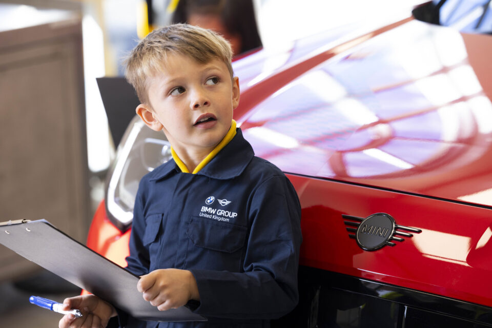 Young children learning about electric vehicle parts as part of a new strategy for recruiting apprentices for UK workshops.